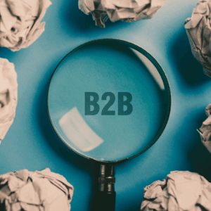 A magnifying glass focuses on the letters "B2B" on a blue background
