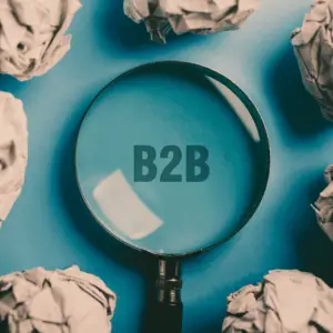 A magnifying glass focuses on the letters "B2B" on a blue background