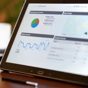 A tablet displaying analytics with a colorful pie chart, line graph, and map overlay.